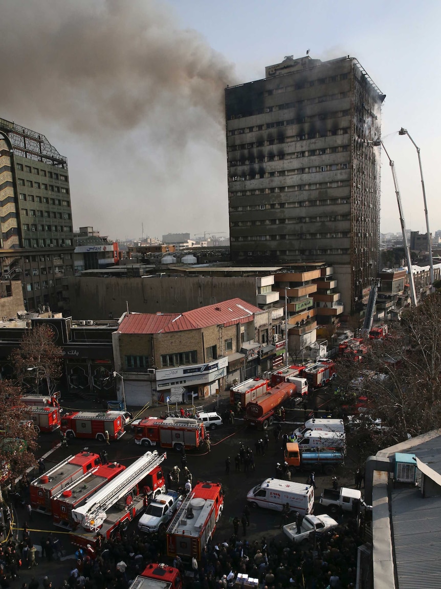 Smoke rises up from the Plasco building where firefighters work to extinguish a fire in central Tehran