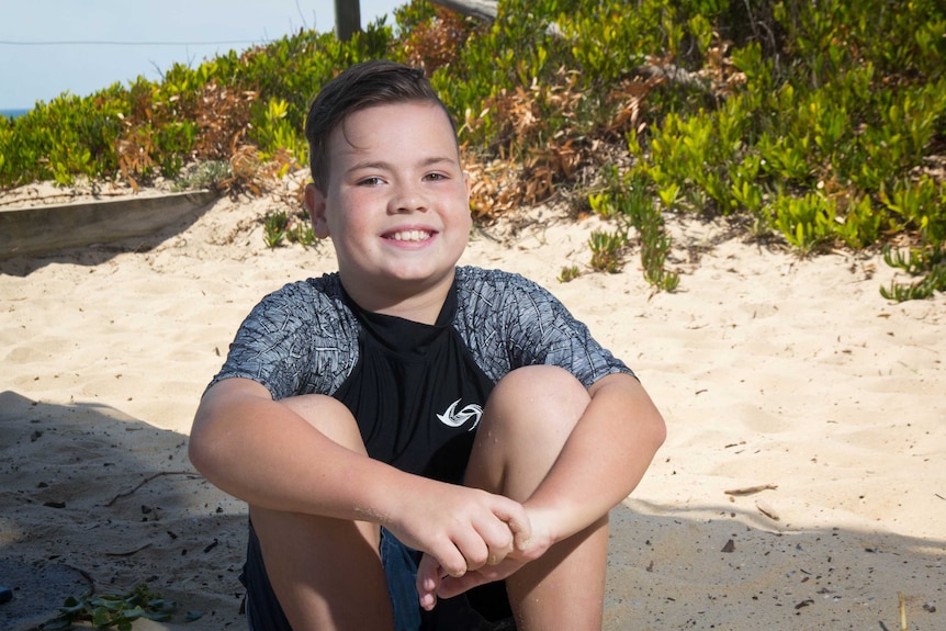 Tyler Ford sits on the sand.