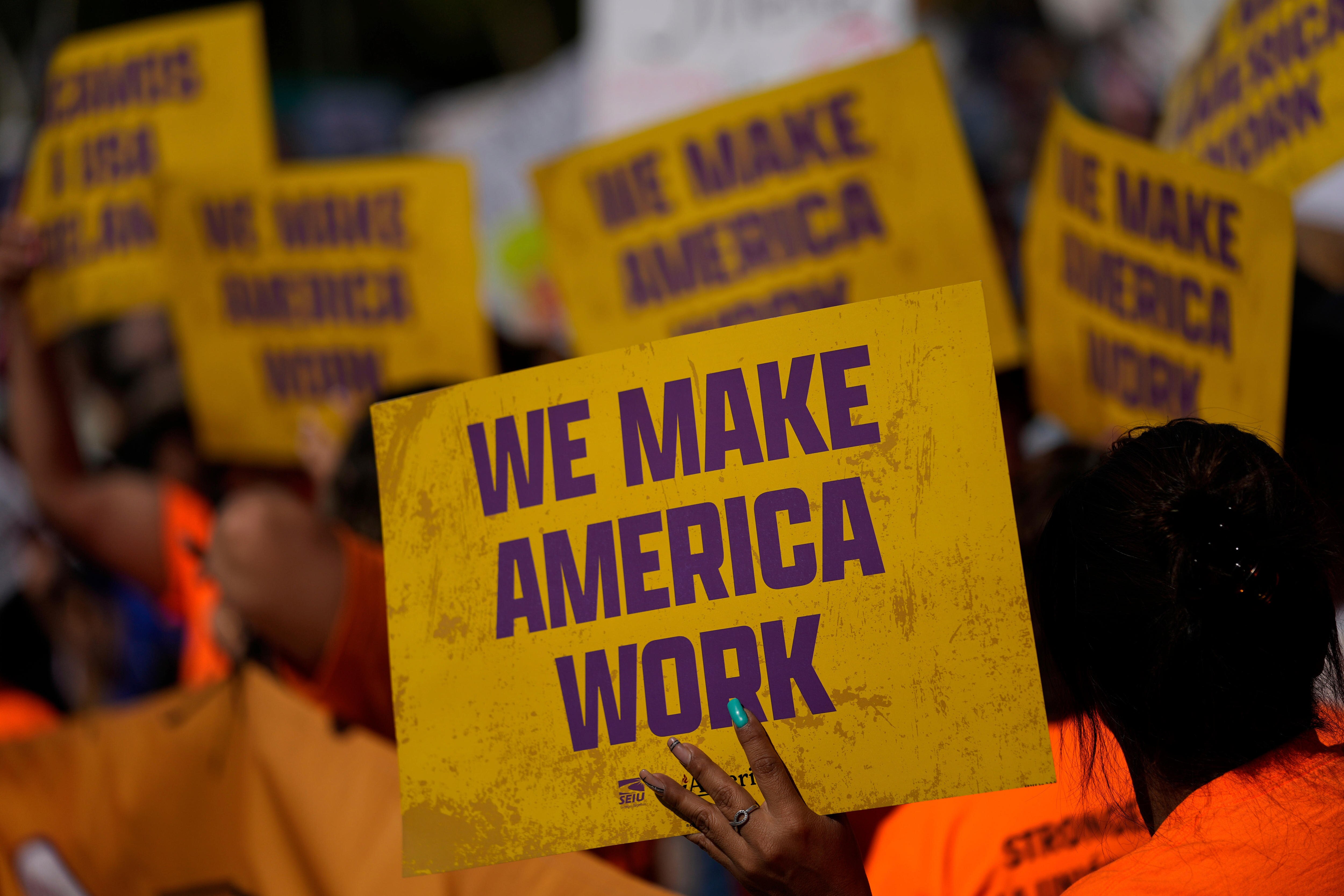 A yellow sign that says 'we make america work' 