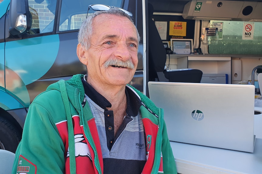 James Wilkinson, wearing a green and red top, lives in a van on the NSW Central Coast. 