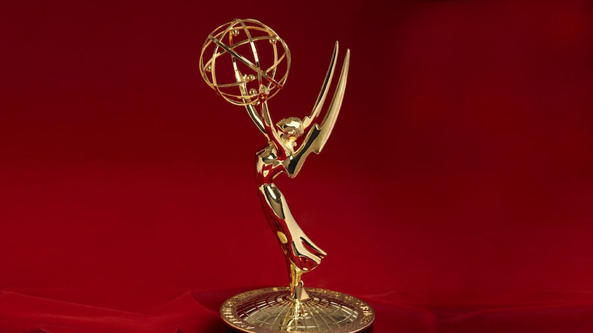 A gold statuette of a winged woman holding an atom above her head