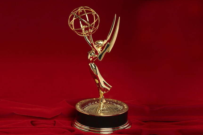 A gold statuette of a winged woman holding an atom above her head