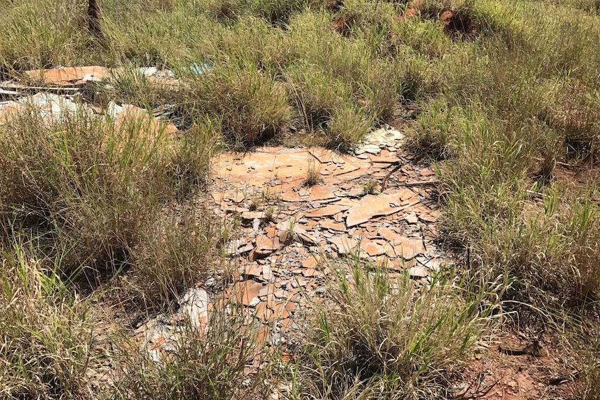 Sheets of broken up asbestos on the ground.