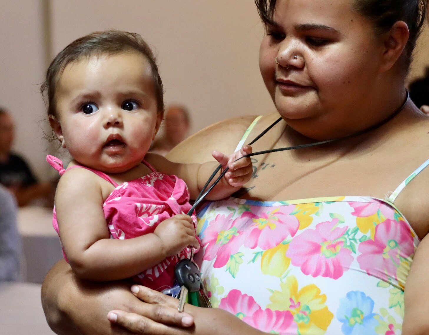 Young Indigenous woman with her baby girl pulling her necklace.