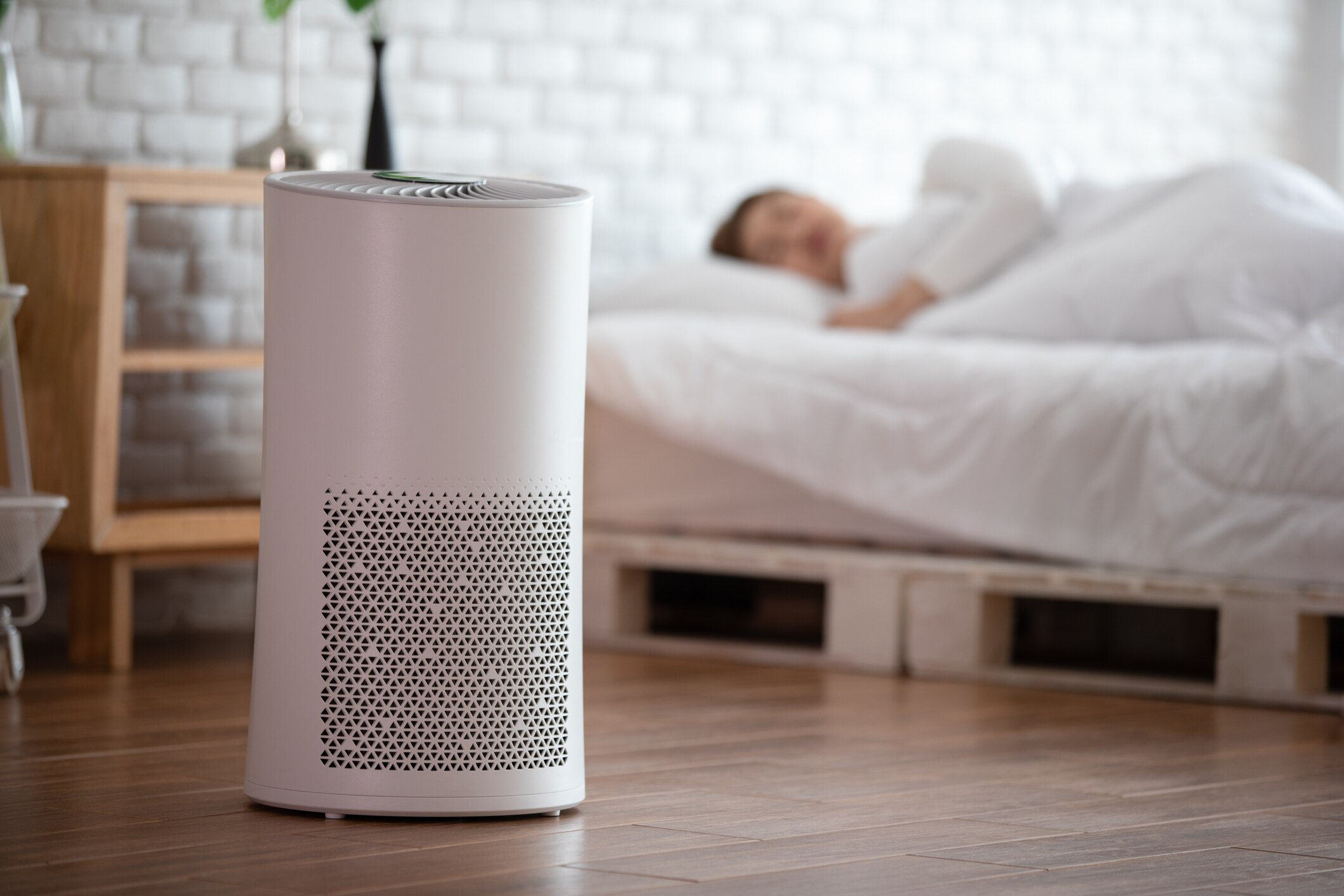 Air purifier in a bedroom. Person sleeping in the background.