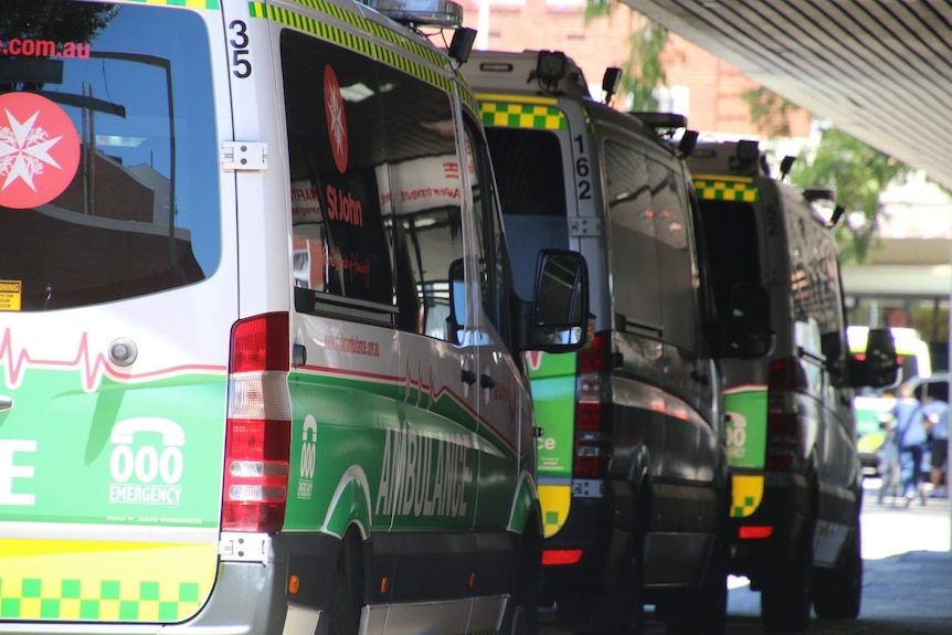 Three ambulances lined up in a row outside a hospital.