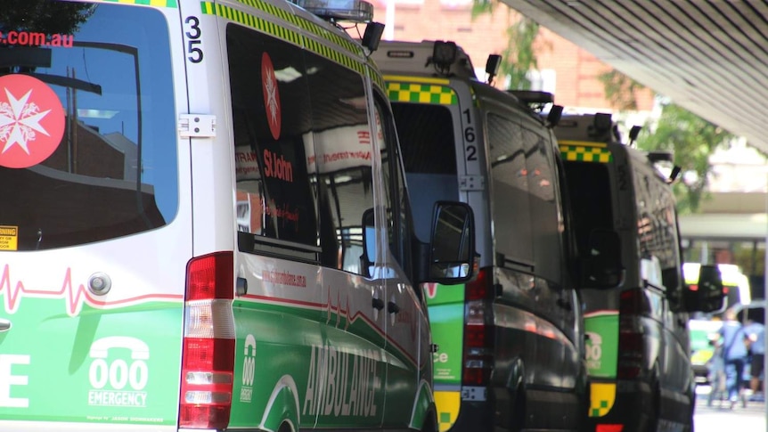 Three ambulances lined up in a row outside a hospital.