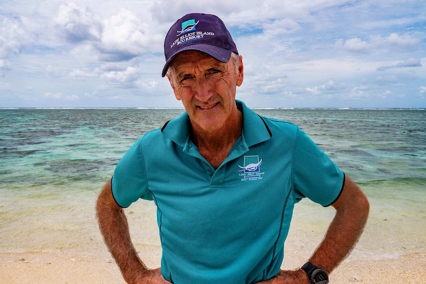 Peter Gash stands on Lady Elliot Island with reef behind him.