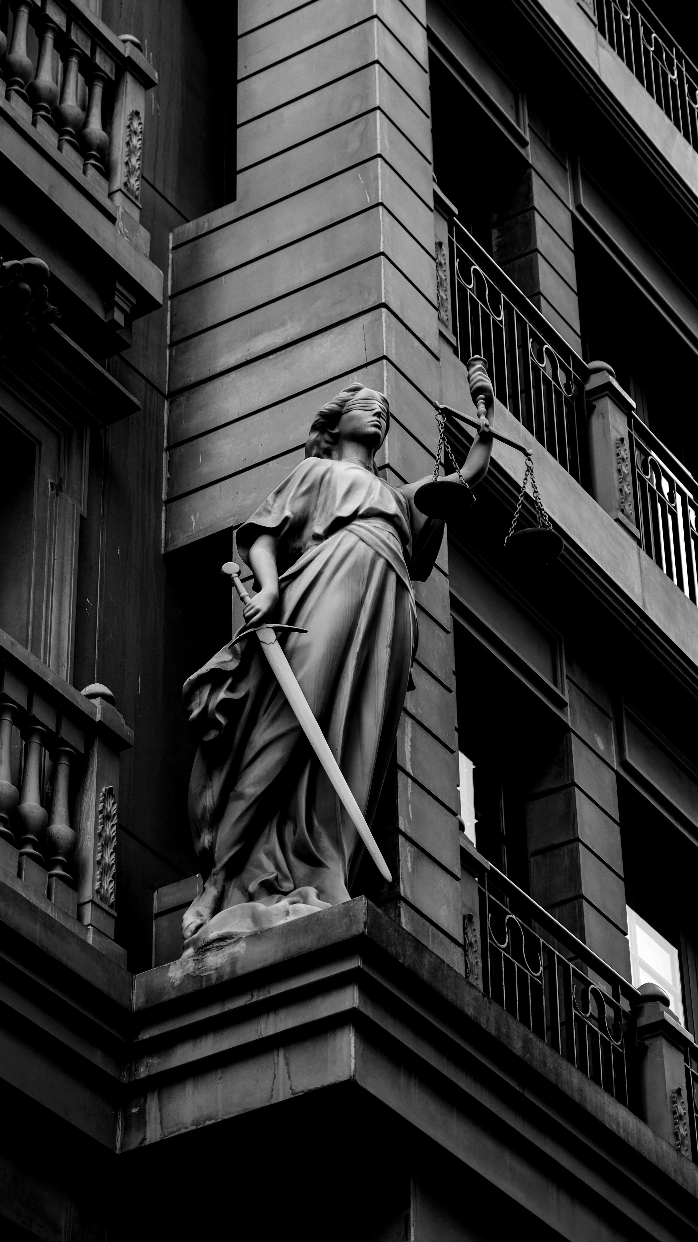 Lady Justice statue outside a stone building or courthouse
