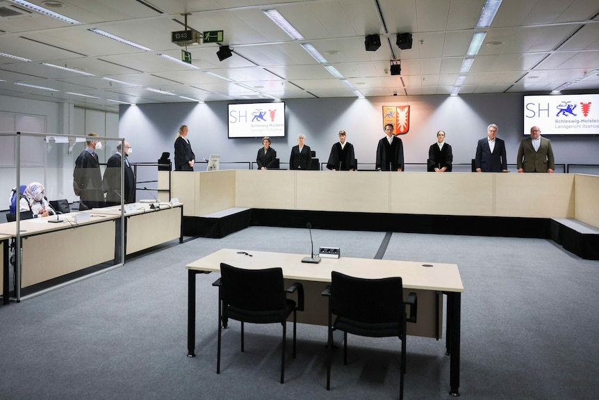 A row of judges and lega officials stand behind desks. 