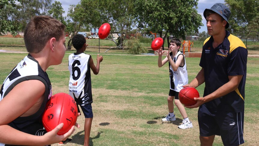 Dom Sheed handpasses to a Hedland Senior High School student during an AFL workshop