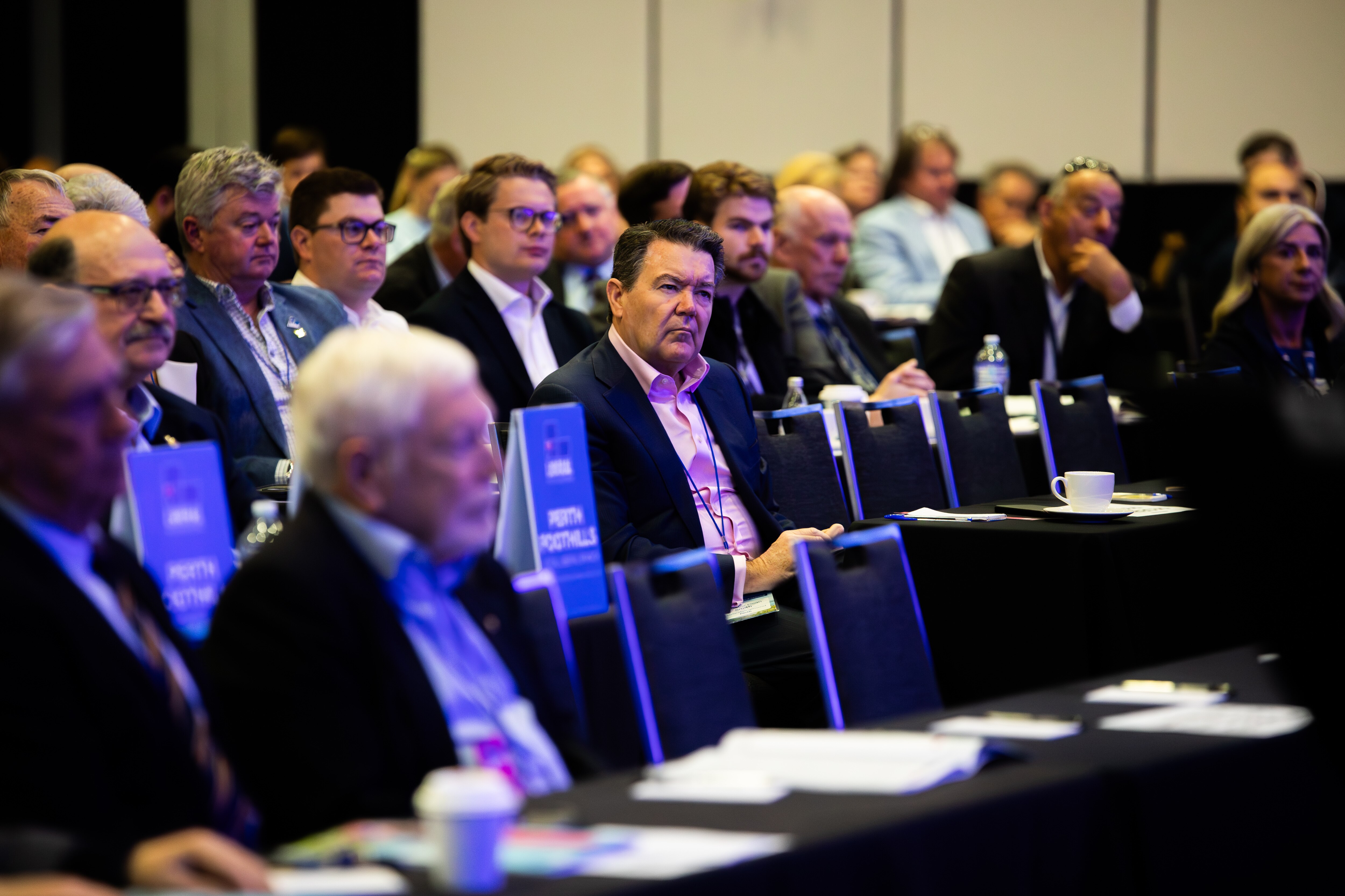 Dean Smith sits in a crowd with few people around him.