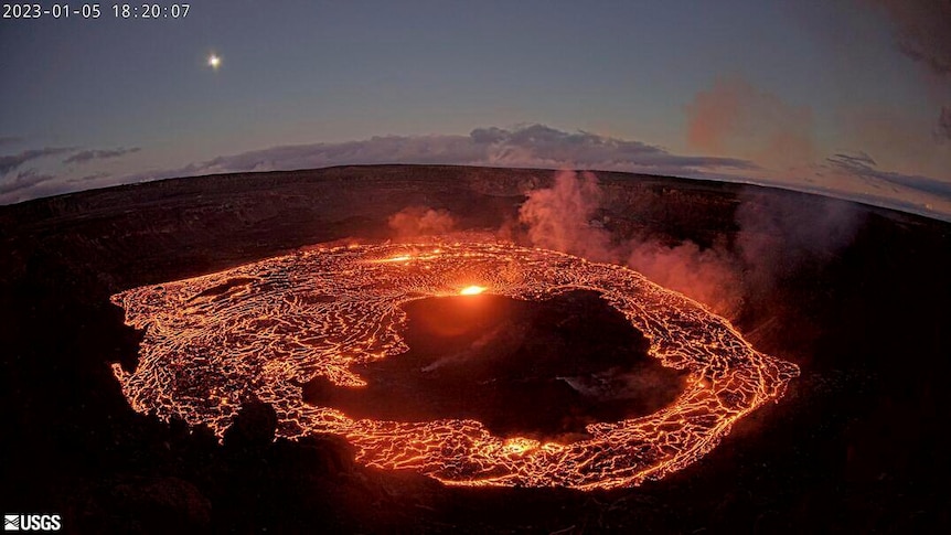 Lava flows in a circle inside a volcano with the sky seen in background. 