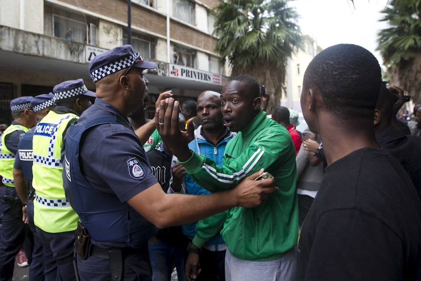 South African police talk to a group of foreign nationals