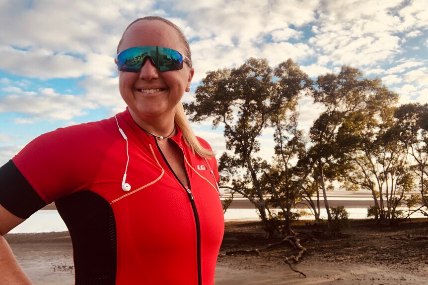 Lisa Wilkins smiles at Nudgee Beach wearing red cycling gear.