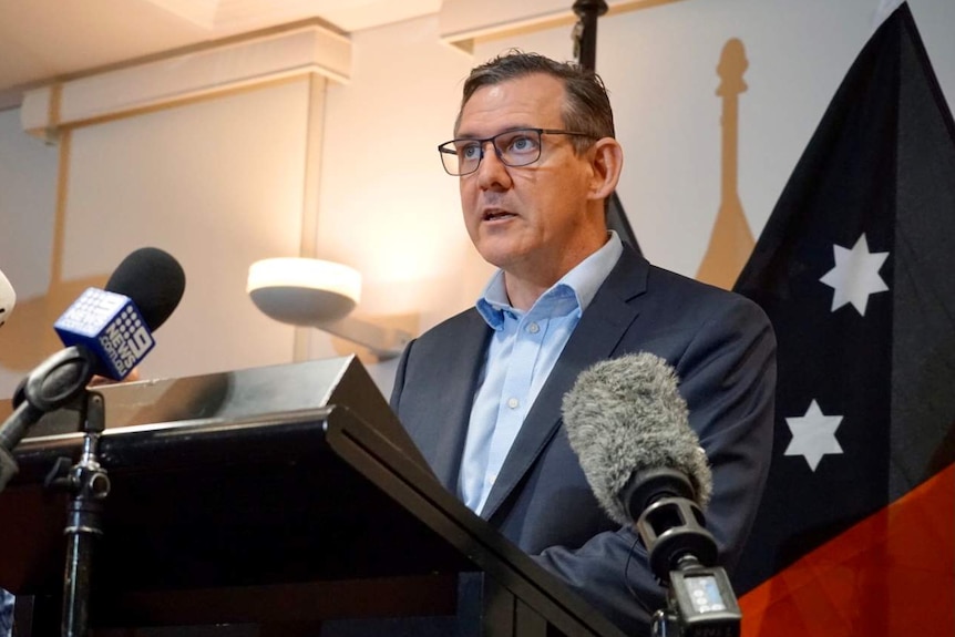 Chief Minister Michael Gunner stands at a lectern with microphones in front of him.