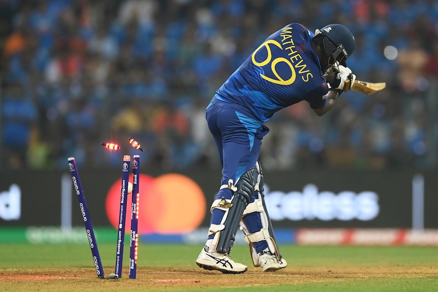 Seen from behind, Sri Lanka batter Angelo Mathews's stumps are broken by a cricket ball as he is bowled.