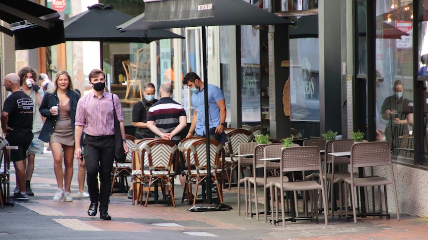 A small number of people walk past cafes in a Melbourne laneway.