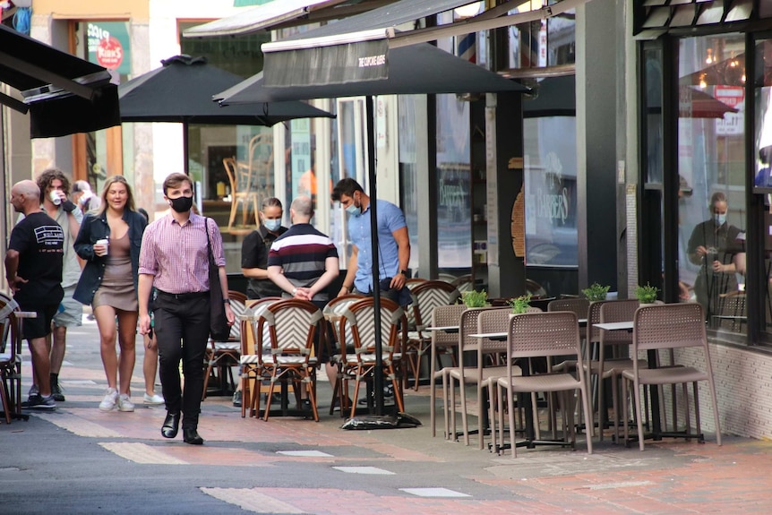 A small number of people walk past cafes in a Melbourne laneway.
