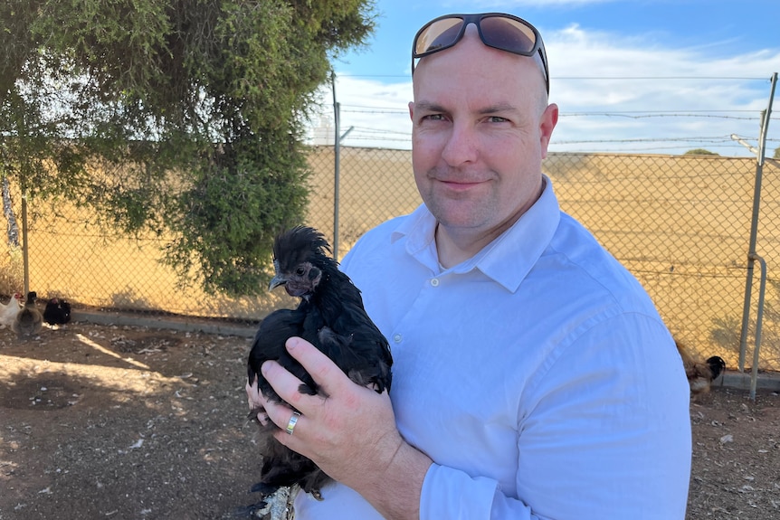 Matthew Carlin holds a black chicken