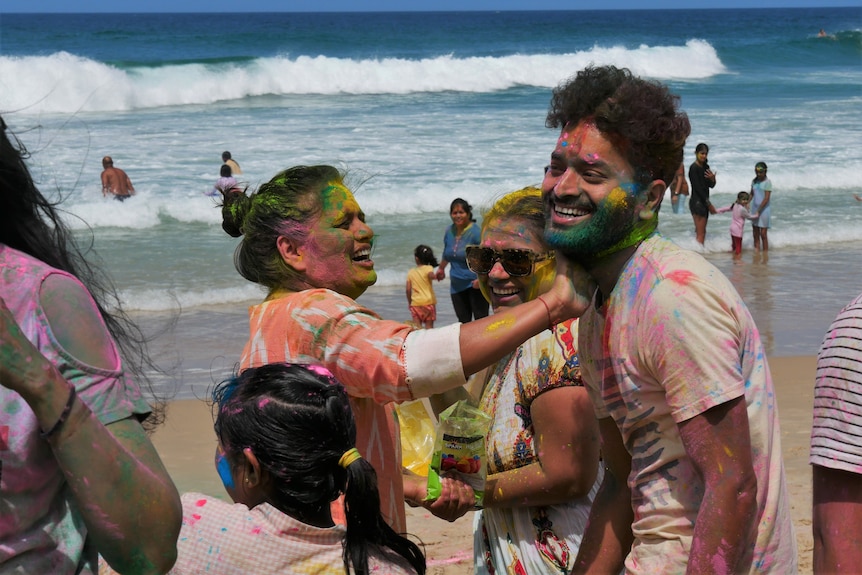 Women laughs and applies coloured powder to friend's face