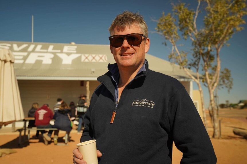 A man wearing sunglasses standing in front on the Birdsville Bakery