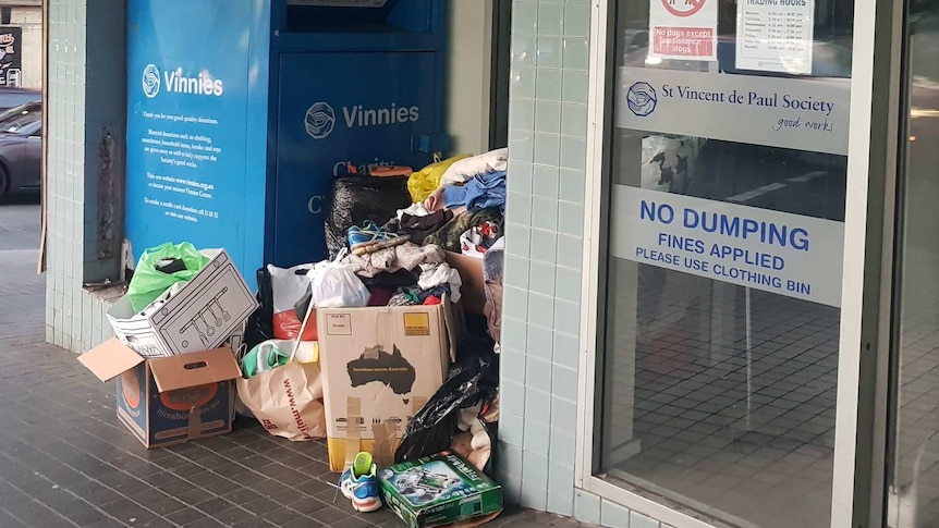 A Vinnies charity bin sits among piles of stuff.