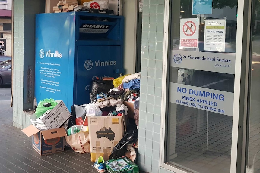 A Vinnies charity bin sits among piles of stuff.