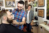 Nathan Meers trims a customer's beard at the Happy Sailors barber shop.