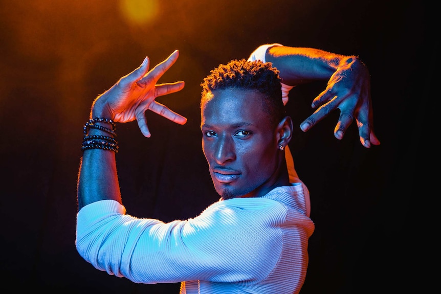 A dramatic colour close-up photo of Dashaun Wesley in a dance pose in front of dark background.