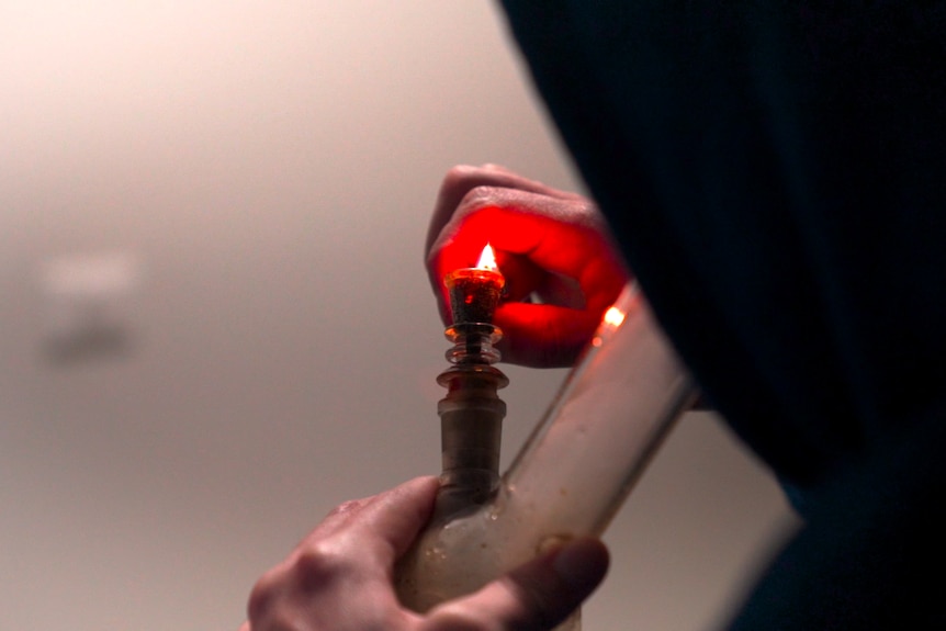 Man lighting a bong with cannabis inside