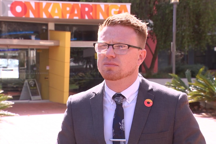 A man in a business suit and glasses outside an Onkaparinga council building