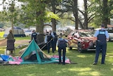Uniformed police take apart a tent.