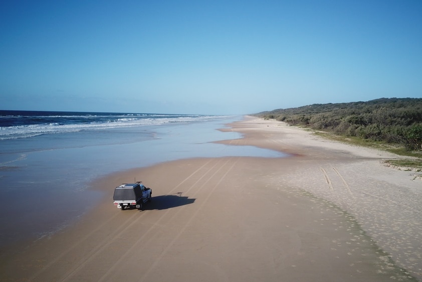 A four-wheel drive car pictured on a deserted coastline.