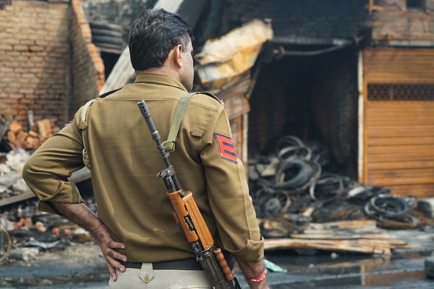 An armed guard looks out of damage from the riots.