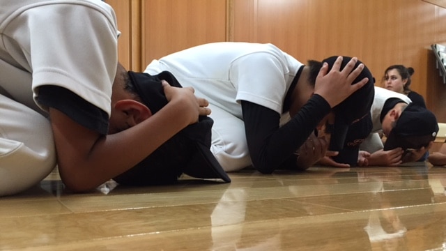 Young boys curl up on the floor in an evacuation drill.