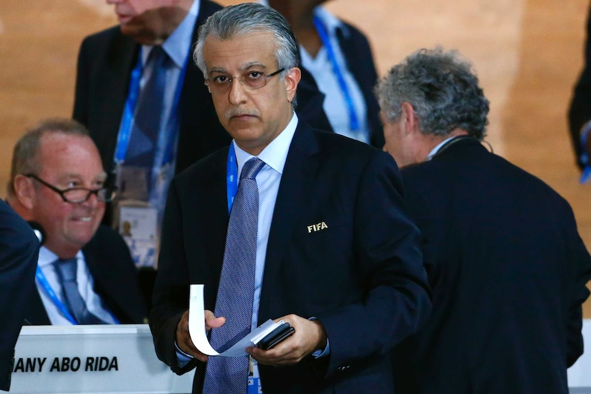 Sheikh Salman bin Al-Khalifa holding a booklet as he looks straight ahead at a FIFA Congress meeting.