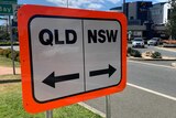 A road sign in Coolangatta reads Qld and NSW with arrows.