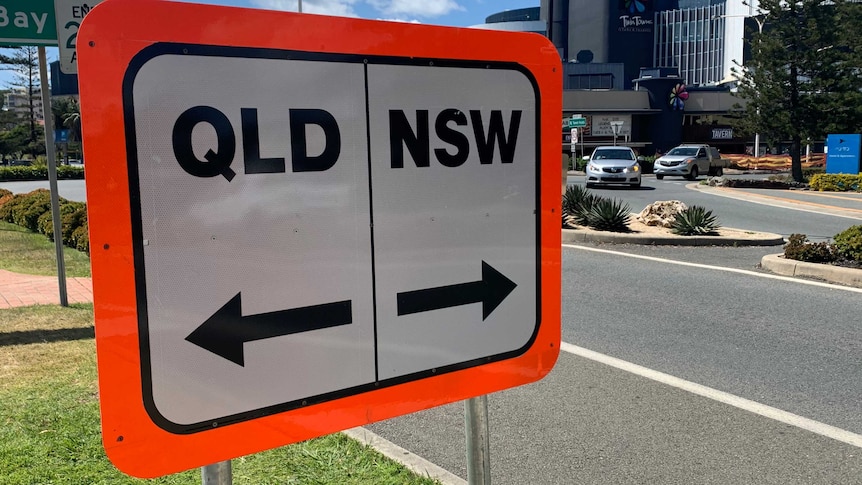 A road sign in Coolangatta reads Qld and NSW with arrows.