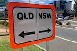 A road sign in Coolangatta reads Qld and NSW with arrows.