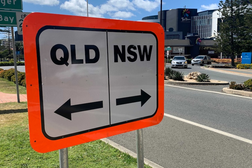 A road sign in Coolangatta reads "Qld" and "NSW", with arrows.