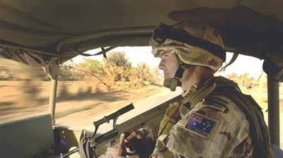 A Royal Australian Air Force squadron leader keeps watch from the back of his vehicle