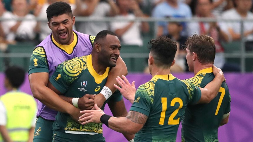 Wallabies players surround one of their teammates as they celebrate a try at the Rugby World Cup.