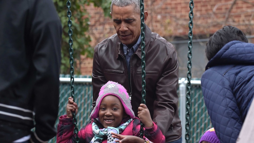 Barack Obama pushes kids on the swings