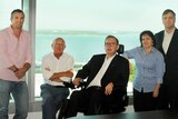 The five board members stand in an office, with a sea view behind them