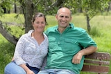 A man and a woman sit smiling together on a bench.