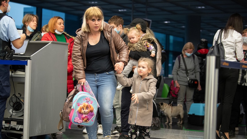 A woman and a young girl pass through a checkpoint at a German airport. They are refugees from Ukraine.