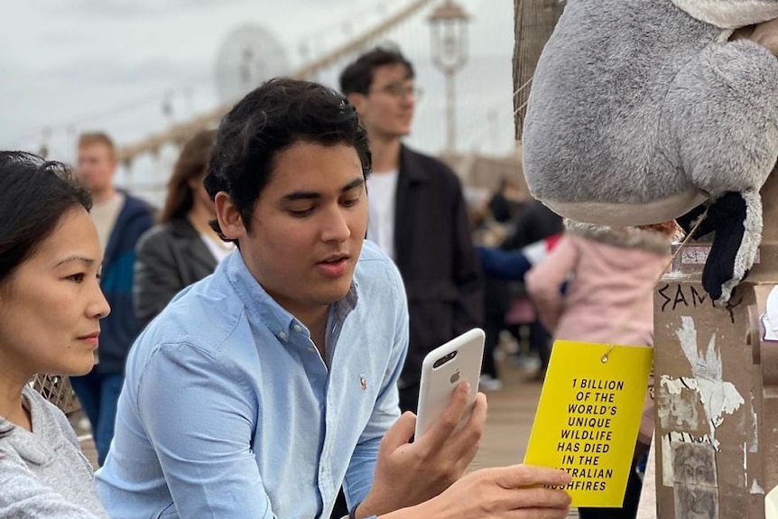 A man taking a photo of a QR code on the back of a koala