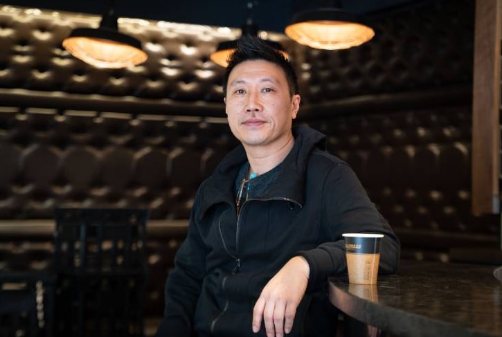 A man in an empty cafe looking solemn.