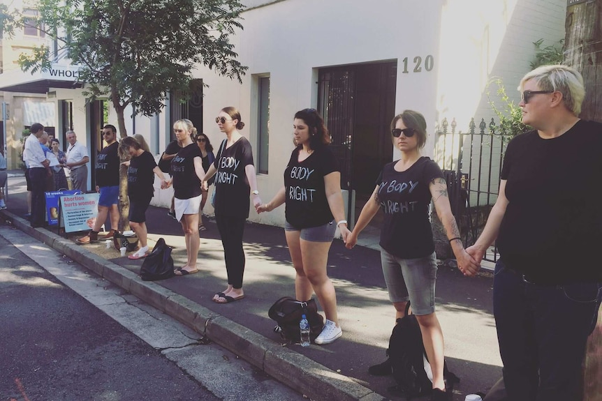 Members of My Body, My Right link arms to create their own human buffer zone outside a clinic in Surry Hills.